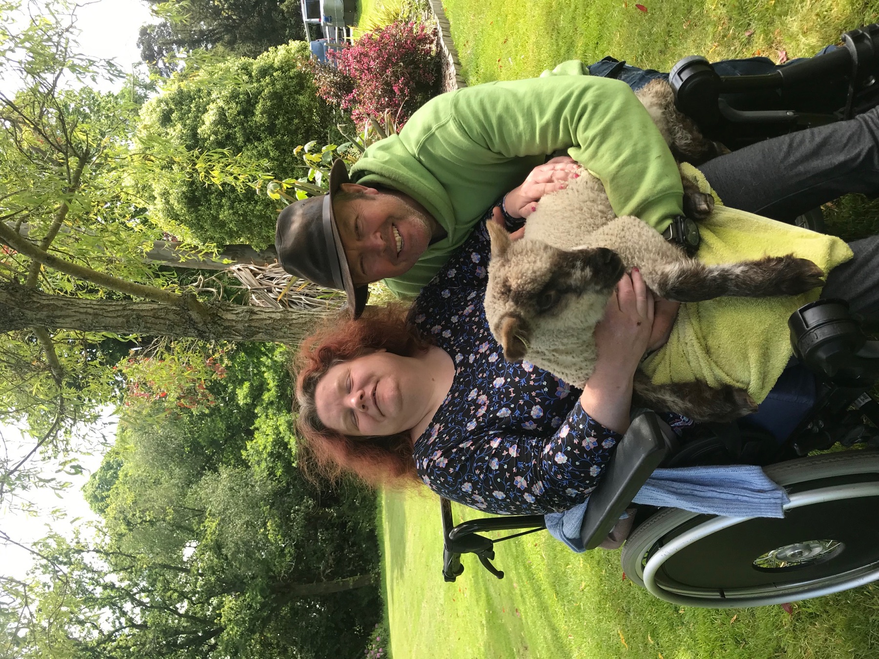 John Brooksbank and a person in care meeting a lamb outdoors